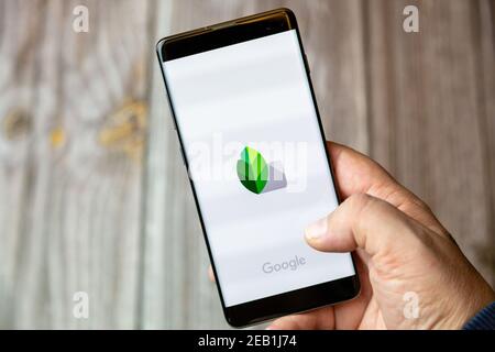 A mobile phone or cell phone being held by a hand with the snapseed app open on screen Stock Photo