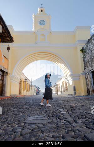 Young Hispanic woman standing under the Arch of Santa Catalina in Antigua Guatemala - tourist on important avenue of colonial Guatemala city with the Stock Photo