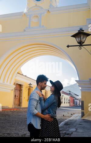 Young hispanic couple under the Arch of Santa Catalina in Antigua Guatemala - tourists in love on important avenue of colonial Guatemala city Stock Photo
