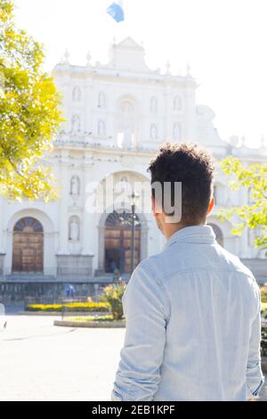 Hispanic young man standing in front of the San Jose cathedral in Antigua Guatemala - young tourist observing the church architecture in the colonial Stock Photo