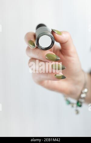 Woman's hand with long nails and light and dark green manicure with bottles of nail polish Stock Photo