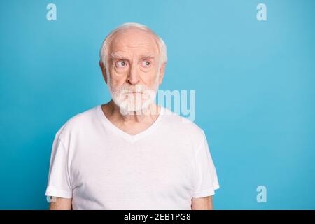 Photo portrait of grumpy old man looking at blank space isolated on pastel blue colored background Stock Photo
