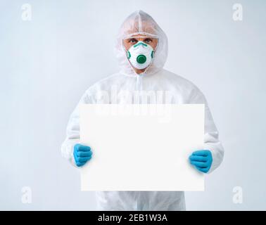 Healthcare worker in protective suit and medical mask holds empty copy space. Health care concept. Stock Photo