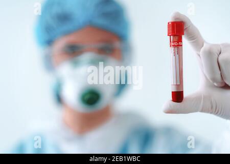 Healthcare worker in protective suit and medical mask blood test result for the new rapidly spreading virus Stock Photo