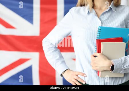 Woman holds notebooks and diaries against background of flags of Britain Stock Photo
