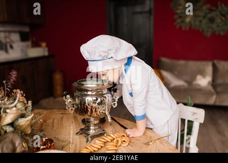 Portrait of a little boy cook holding pan at the kitchen. Different occupations. Isolated over white background. Twin brothers Stock Photo