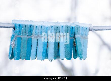 Frozen clothes pegs in winter time - Ice covered. Stock Photo