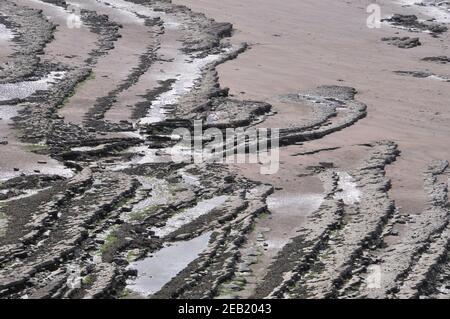 Limestone ridges appear through the sand on the Bristol Channel beach at Kilve on the coast at the foot of the Quantock Hills in Somerset. Stock Photo