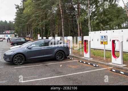 A Tesla Electric car is charged at a Tesla charging point at a service station on the M3 motorway, UK Stock Photo