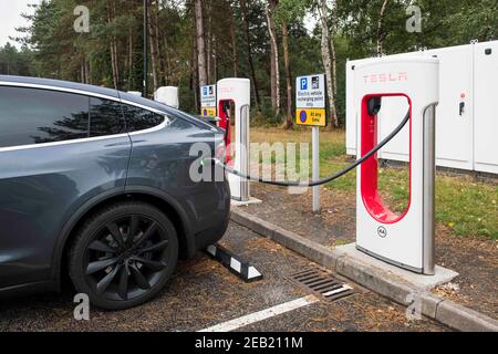 A Tesla Electric car is charged at a Tesla charging point at a service station on the M3 motorway, UK Stock Photo