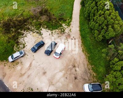 Aerial view of a few cars parked in a small parking lot along the road on Monsanto Hill next a football field, Lisbon, Portugal. Stock Photo