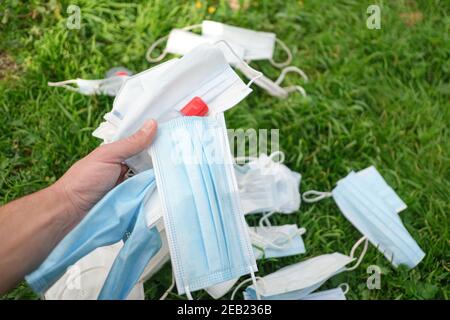 Used protective face mask and hand sanitizer bottle discarded on natural ecosystem,covid19 pandemic waste pollution Stock Photo