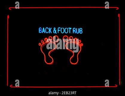 A neon sign in a New York City window advertising back and foot rubs available inside the business. Stock Photo