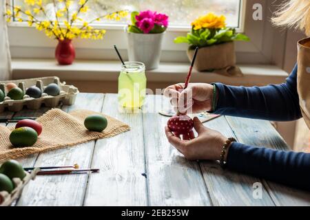 Painting and decorating eggs for Easter holiday. Woman coloring egg on table at home Stock Photo