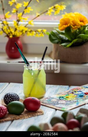 Paintbrush in glass of water during coloring and painting decoration. Preparing eggs for Easter holiday celebration. Art and craft concept Stock Photo