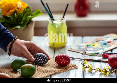 Female hand preparing eggs for Easter holiday. Homemade decoration. Coloring and painting easter egg on table at home. Stock Photo