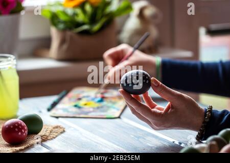 Homemade coloring Easter egg. Woman creative painting and decorating eggs on table at home. Preparation for religious celebration Stock Photo