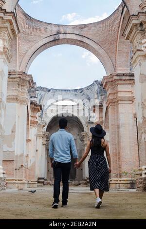 Young couple on vacation visiting famous ancient ruins - Travelers enjoying their romantic vacation in Antigua Guatemala - Couple walking hand in hand Stock Photo