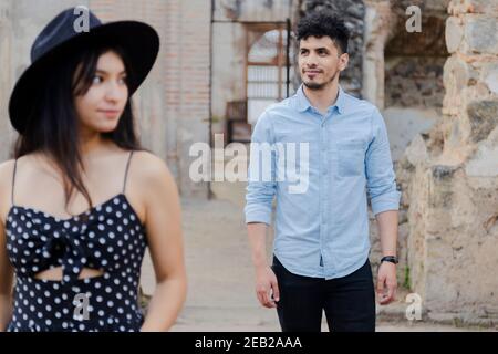 Creative portrait of Hispanic couple among famous ruins of Antigua Guatemala-Hispanic young man smiling looking at the horizon with his girlfriend in Stock Photo