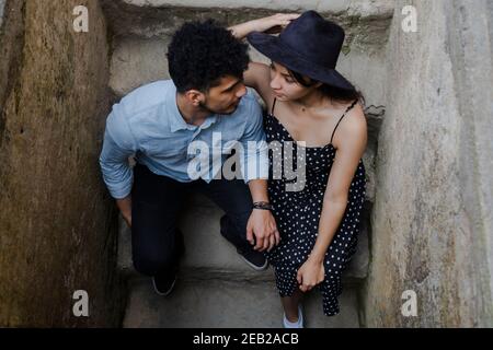 Top view of couple sitting on the narrow bleachers looking at each other - Couple in love on vacation in colonial city - Travelers in Antigua Guatemal Stock Photo