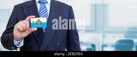 Cropped image of businessman holding plastic credit card with San Marino. Background blurred. Stock Photo