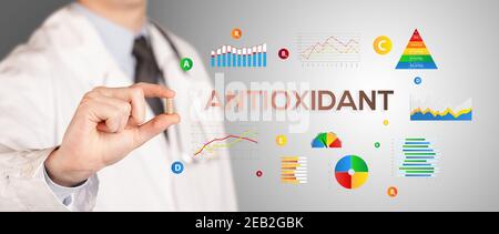 Nutritionist giving you a pill with ANTIOXIDANT inscription, healthy lifestyle concept Stock Photo
