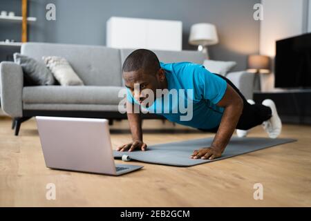 African American Man Doing Online Fitness Pushup Workout At Home Stock Photo
