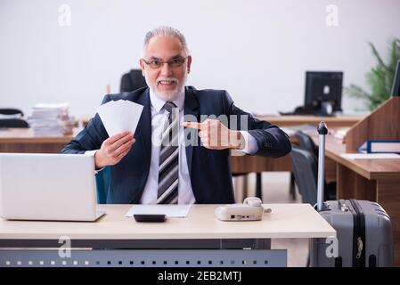 Aged male employee preparing for travel in the office Stock Photo