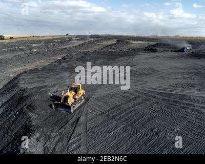 Bulldozer is pushing hard coal. Large coal heap. Stock Photo