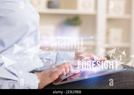 Close up hands using tablet with FORESIGHT inscription, modern business technology concept