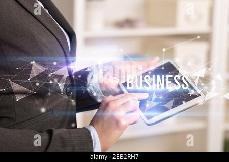 Close up hands using tablet with BUSINESS inscription, modern business technology concept