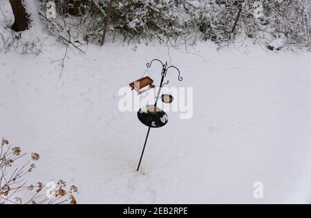 Bird feeders and the pole on the ground covered with snow after a winter storm Stock Photo