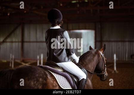 Young woman is engaged in equestrian sports, training on horseback Stock Photo