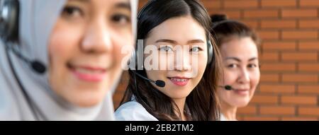 Diverse Asian women working in call center office as customer service operators, panoramic banner Stock Photo