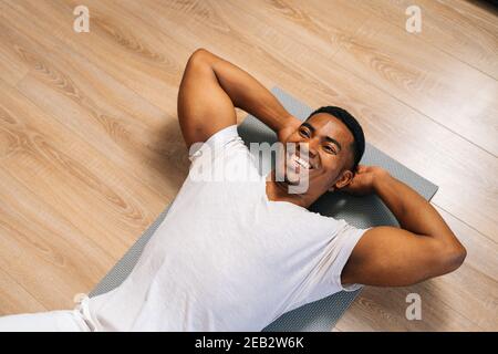 Top view of fit African-American man practicing abs crunches, training abdominal muscles on floor. Stock Photo