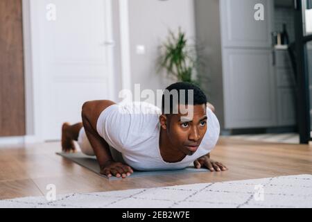 Close-up view of Focused African-American man doing push-up on floor looking away. Stock Photo