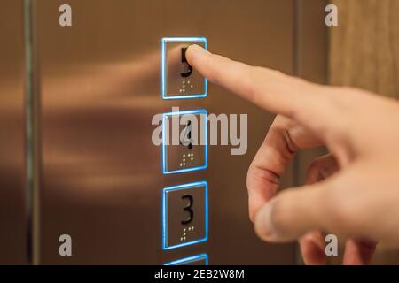 finger presses the number on the elevator button Stock Photo