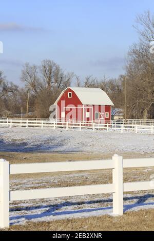Kansas red and white barn with a fence and tree's with blue sky out in ...