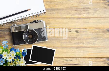 Top view image of blank notebook and vintage camera with two blank photo frames on wood table or office desk background. space for design Stock Photo