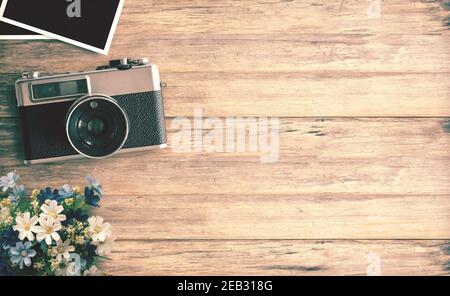 Top view image of vintage camera with two blank photo frames on wood table or office desk background. space for design. retro filtered Stock Photo