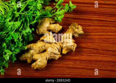 Raw and medicinal plant root Ginger pieces with coriander leaves on the table Stock Photo