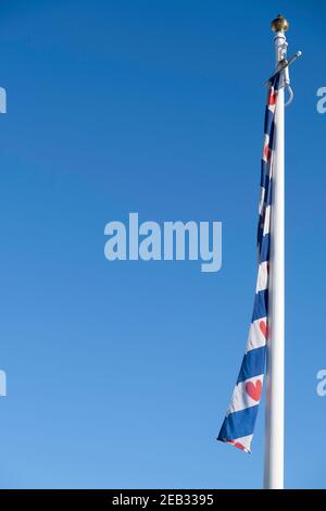 White mast with the flag of the province of Friesland. Blue with seven red seeblatts (or 'Pompebled') and four blue and three white diagonal stripes Stock Photo
