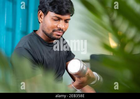 Young man doing exercise using book due coronavirus covid-19 pandemic lock down - concept of new normal, home gym, health care and lifestyle Stock Photo