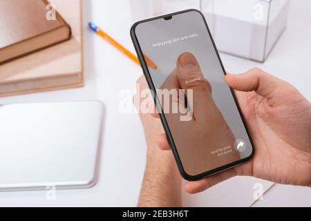 Man using a phone to recognize a problem with his nail Stock Photo