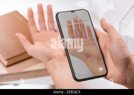 Man using a phone app to recognize a disease on inner side of his fingers Stock Photo
