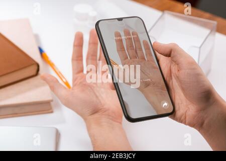 Man using a phone app to recognize the disease on his palm Stock Photo