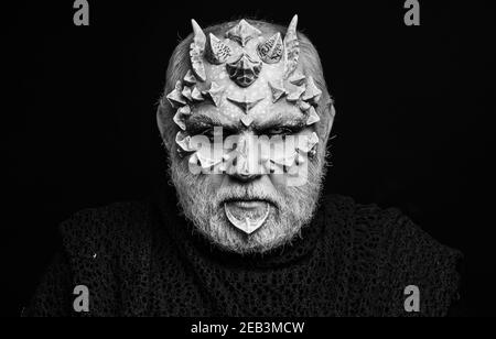 Devil isolated on black. Alien or reptilian makeup with sharp thorns and warts. Horror and fantasy concept. Man with dragon skin and beard. Monster. Stock Photo