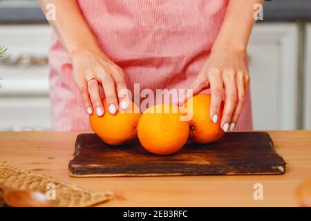 Unrecognizable woman holding oranges while standing in kitchen Stock Photo