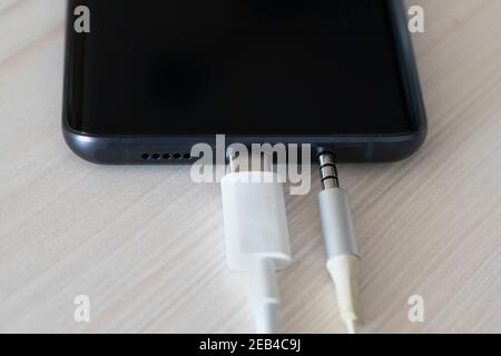 Close up Mobile phone Charger with USB Type-C USB-C. USB type C cable charger and port of the phone. Connection 3.5 mm audio jack to a black mobile ph Stock Photo