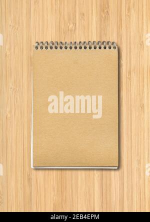 Spiral closed notebook mockup, brown paper cover, isolated on wood background Stock Photo